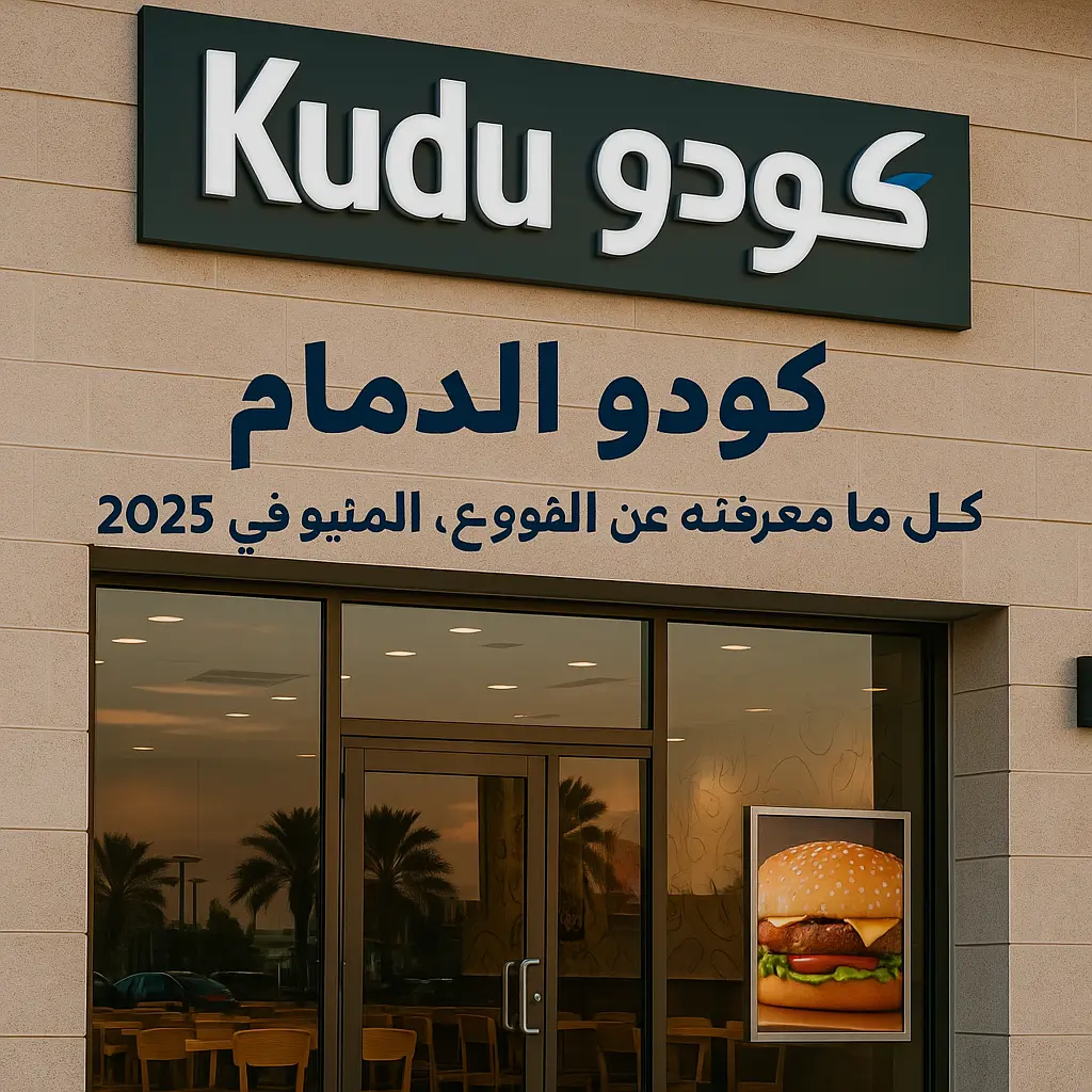واجهة مطعم كودو الدمام تظهر بوضوح الشعار باللغتين العربية والإنجليزية، مع باب زجاجي وصورة لبرجر، في جو مسائي دافئ يعكس النخيل في الخلفية.